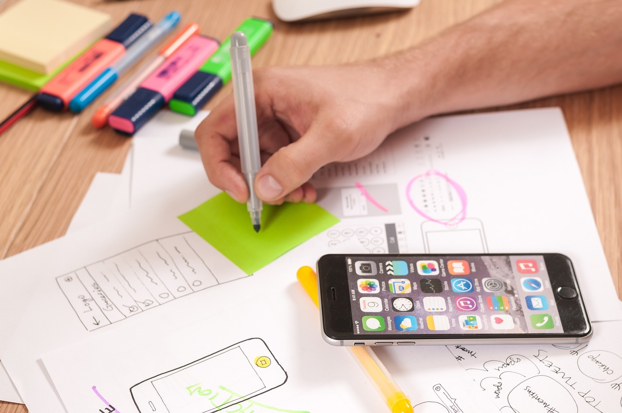 Croquis d’interface mobile, post-its et smartphone illustrant le processus de conception UX pour le développement d’applications sur mesure avec TkeeCode.